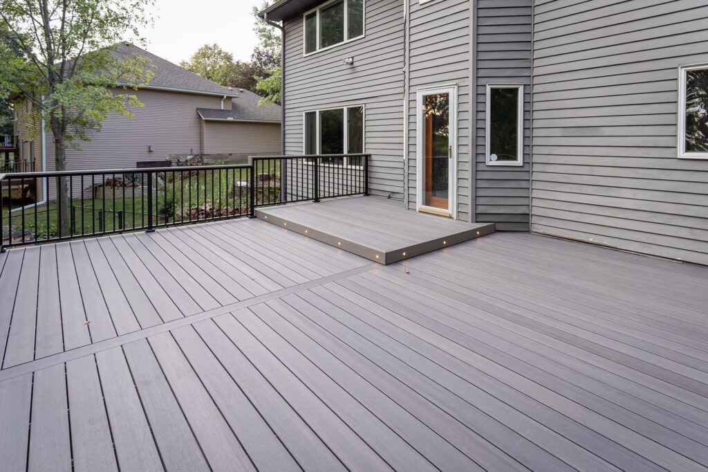 Large gray composite deck with a raised platform with riser lights in front of the door. 