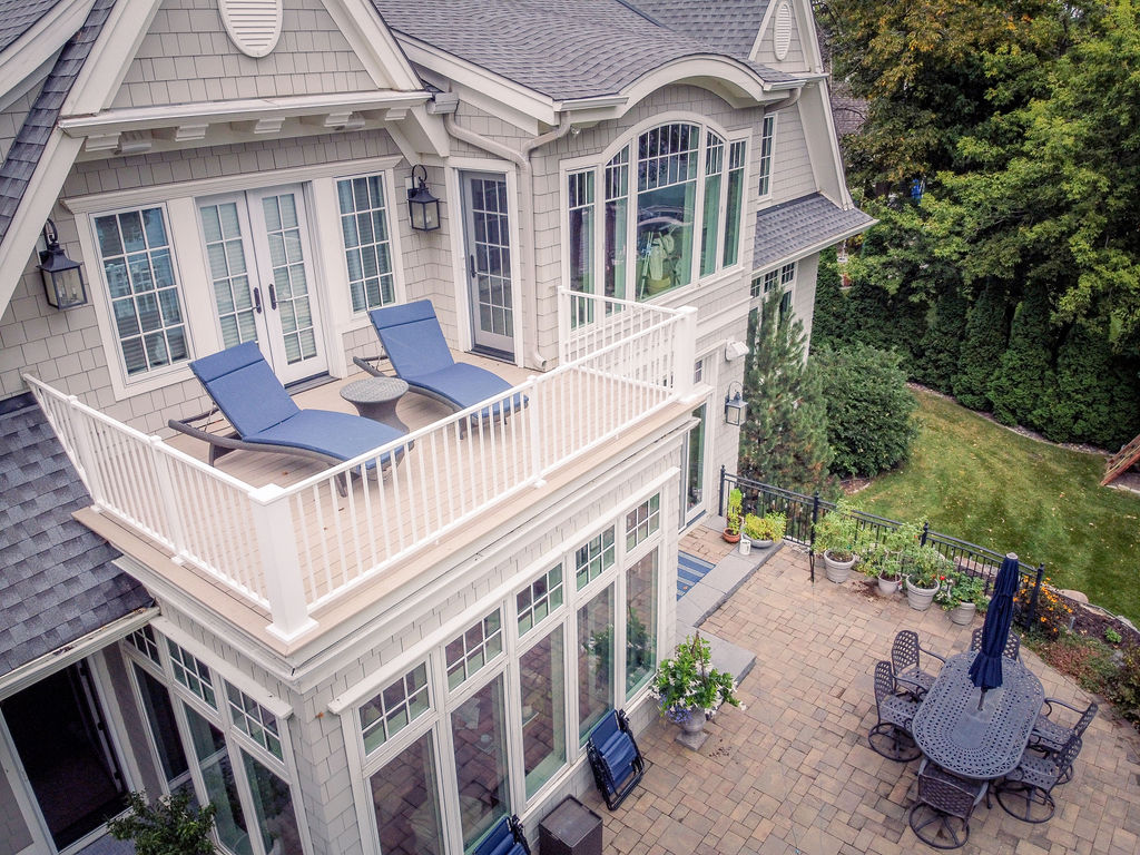 Alternate angle showing composite deck on top of a sunroom with two lounge chairs. 