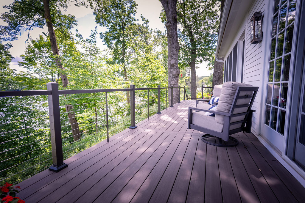 Low-maintenance deck with cable railing and furniture overlooking a wooded area.