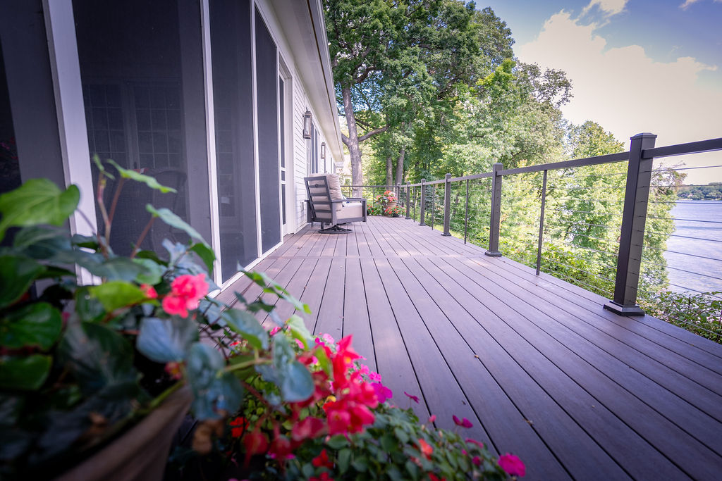 TimberTech Advanced PVC deck in American Walnut with cable railing and red flowers.