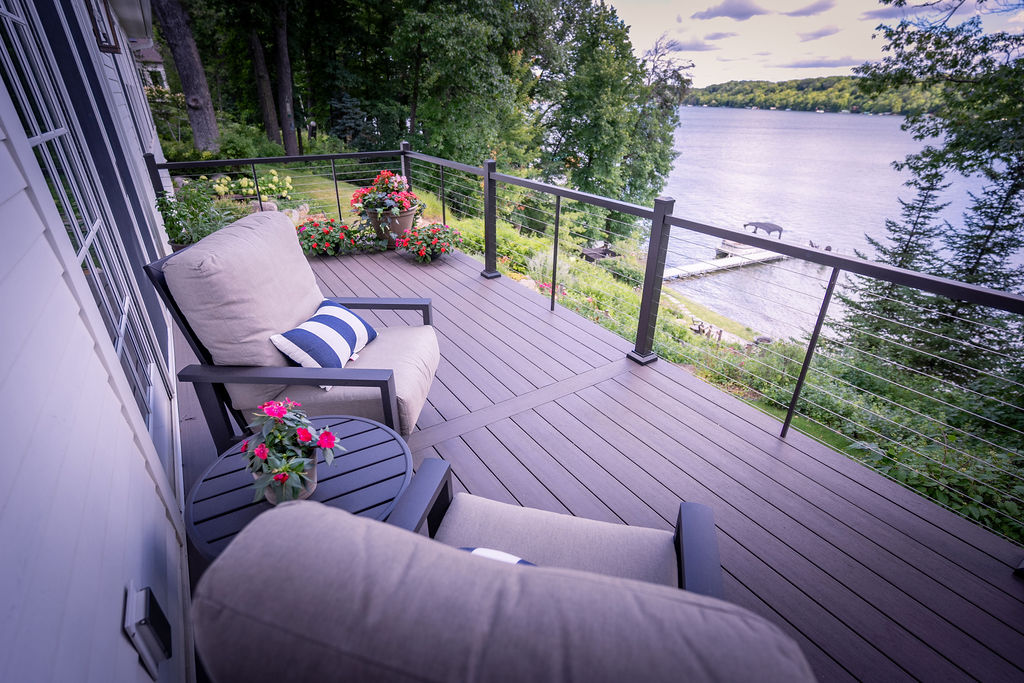 Custom low-maintenance deck with furniture overlooking a large wooded lake.