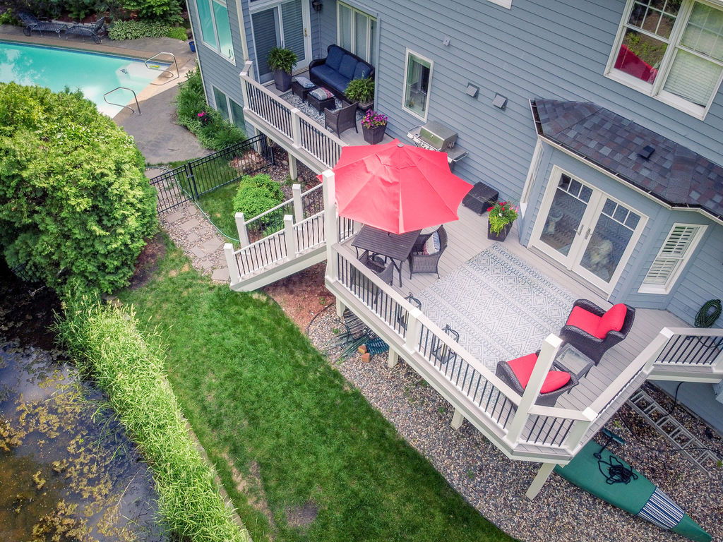Aerial view of a deck alongside a house with red furnishings.