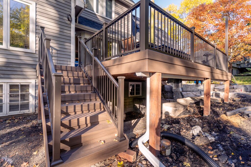 Composite deck and staircase with complementary bronze aluminum railing and a wood frame during the fall. 