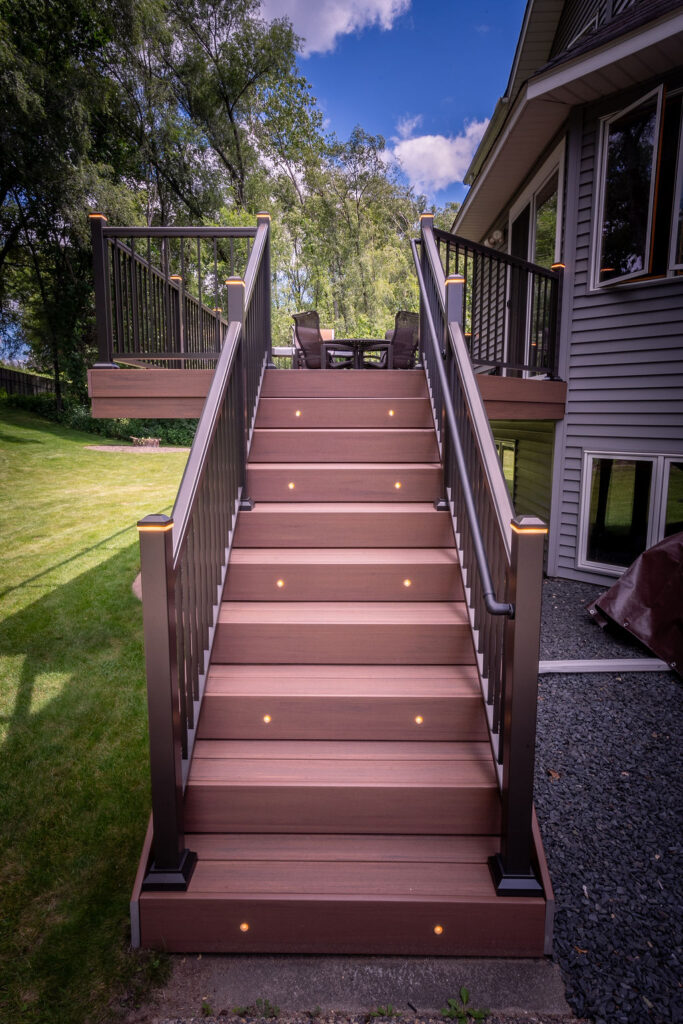 Front view of low-maintenance deck stairs with integrated riser lights on every other stair, as well as integrated post cap lights on every railing post. 