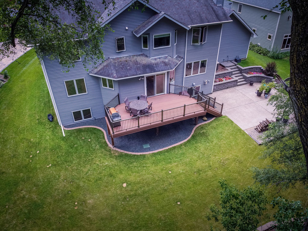 Wide aerial view of a TimberTech Advanced PVC deck on the back of a house, with a staircase leading to a paver patio. 