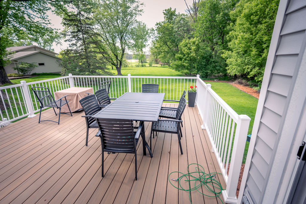 TimberTech Composite deck with white railings and outdoor dining furniture on a summer day. 