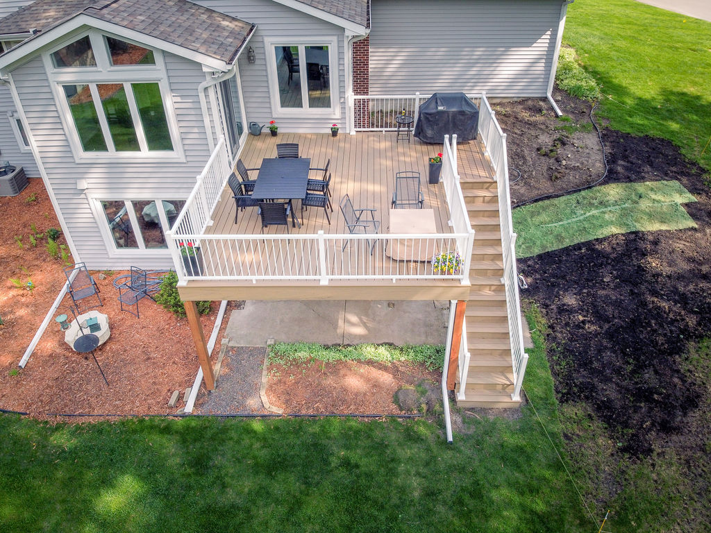Aerial front view of second-story low-maintenance deck with white railing and staircase. 