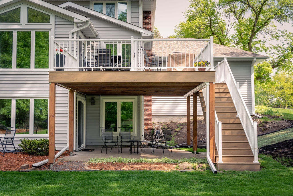 Front ground view of residential composite deck with patio underneath. 