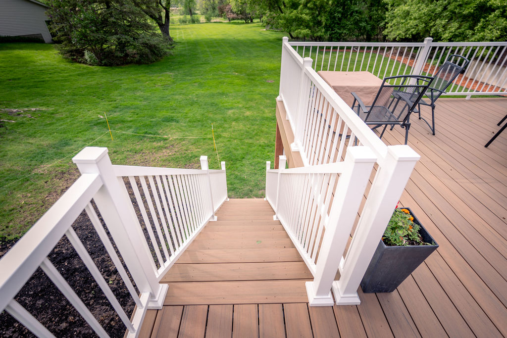 Top view of beige low-maintenance deck staircase with white railing. 