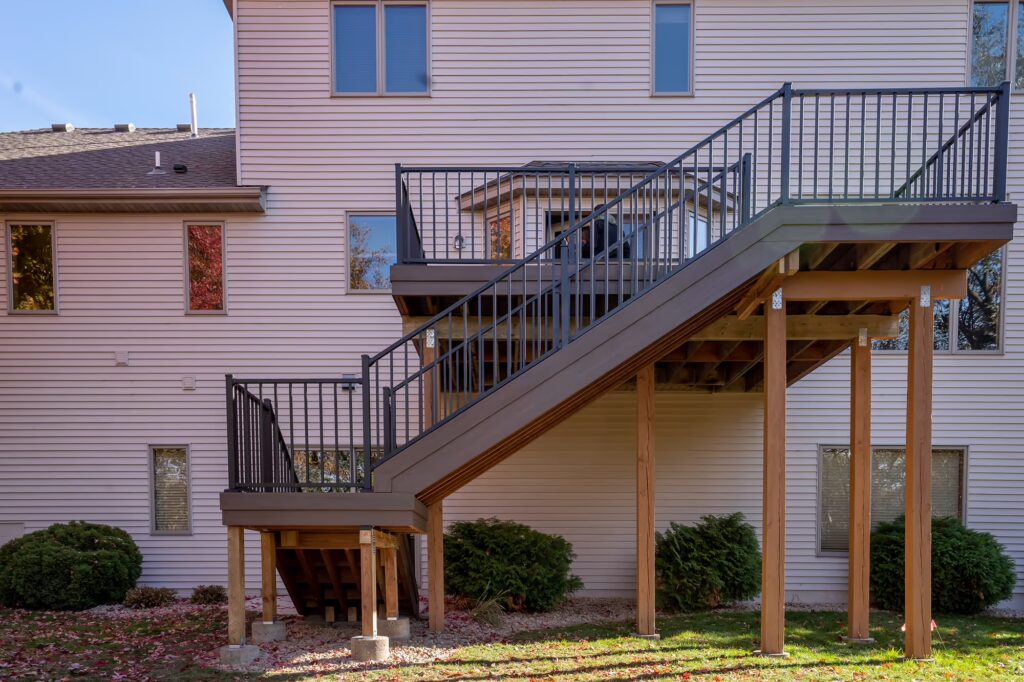 Side view of deck and L-shaped staircase on the back of a house.