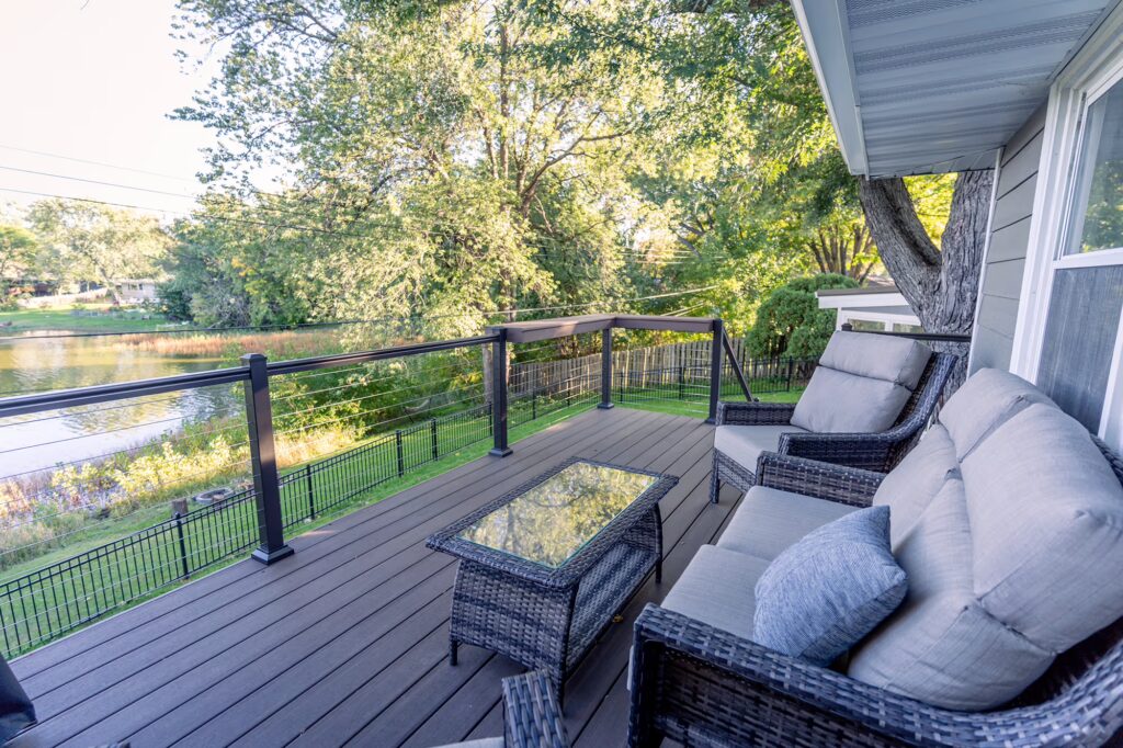 Cozy low-maintenance deck with outdoor furniture, overlooking a small lake.