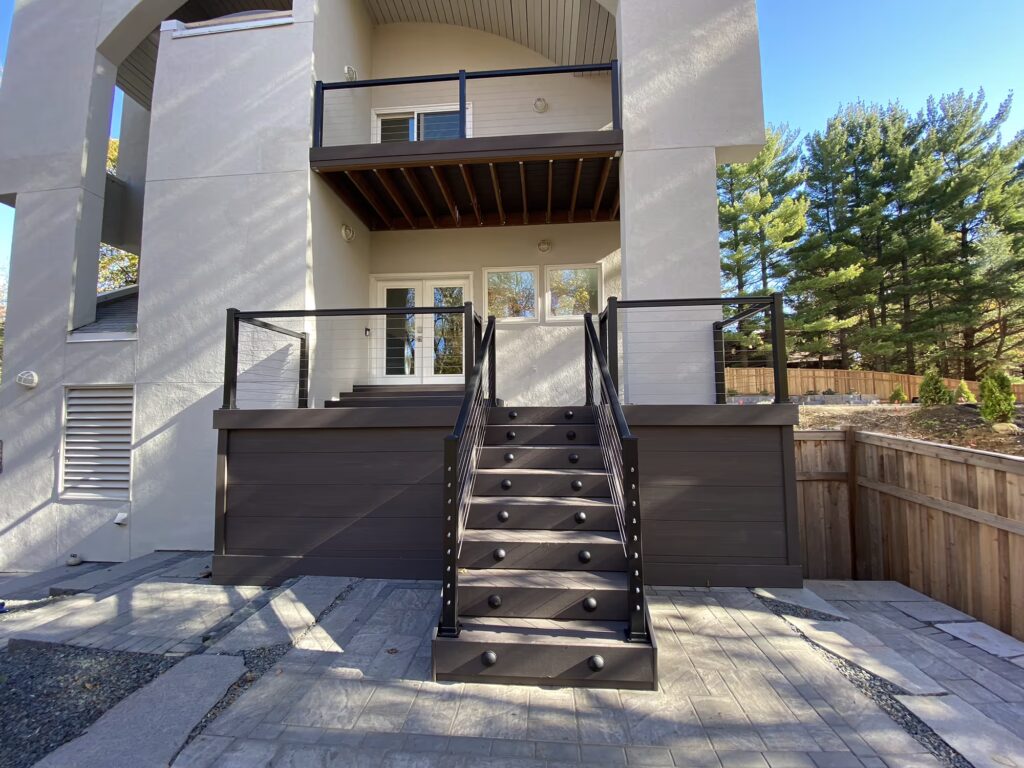 Front view of front porch deck with stairs to ground level, and matching balcony deck above.