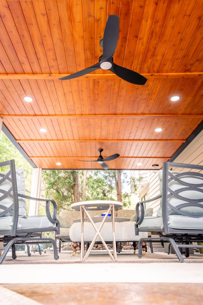 Low-angle view of under-deck cedar ceiling with recessed lighting and integrated fans.