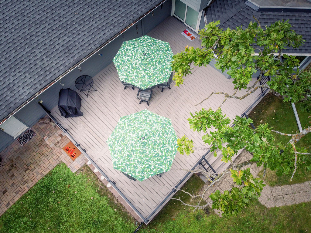 Top aerial view of a gray TimberTech Advanced PVC deck furnished with two green umbrellas.