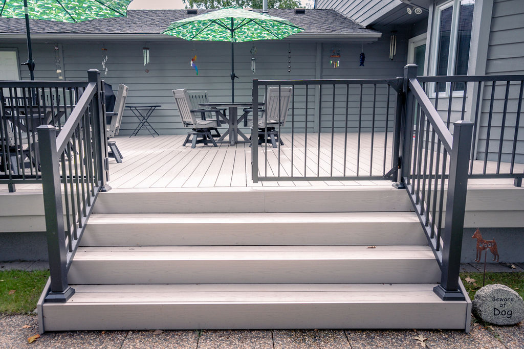 Custom wide deck stairs on platform deck using TimberTech advanced PVC, with one of the gate doors closed and one open.