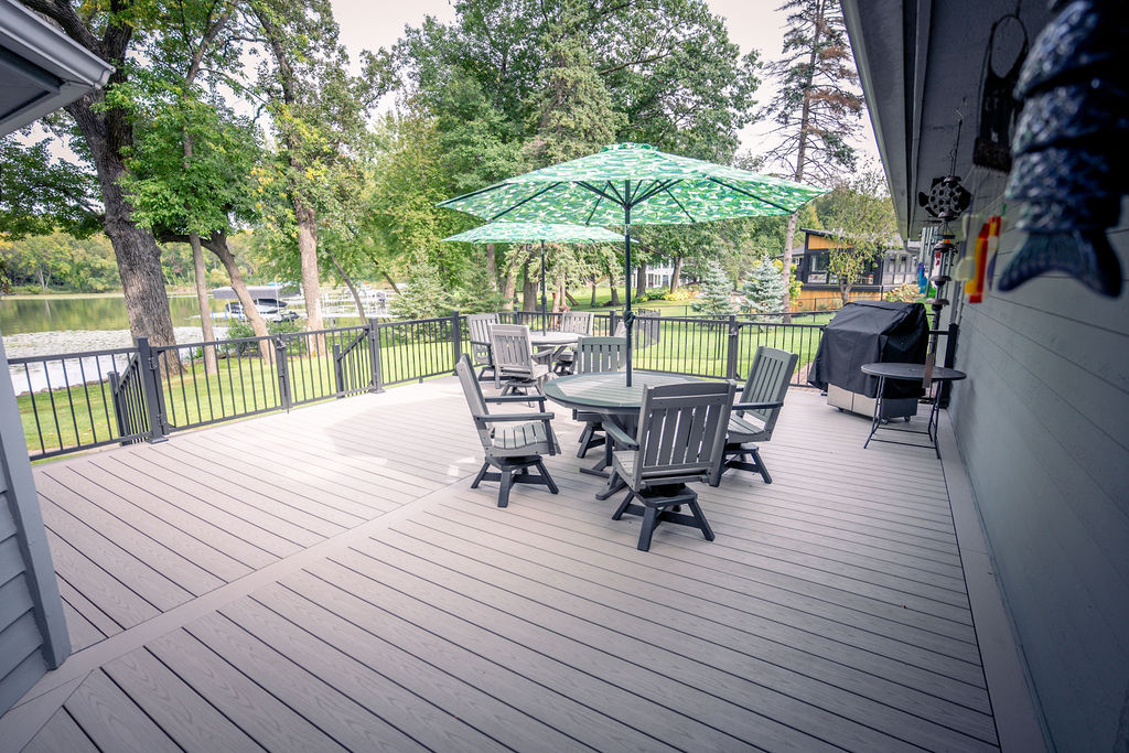 Large PVC deck with table, chairs, and umbrella.