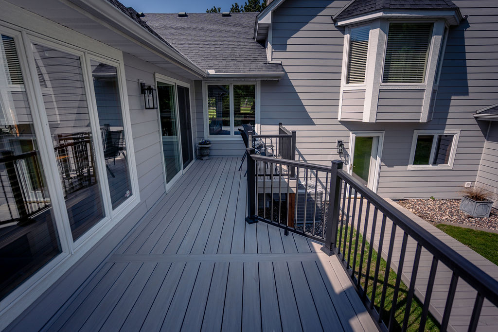 TimberTech Advanced PVC deck in Boardwalk spanning the length of a house with two bump-outs for seating.