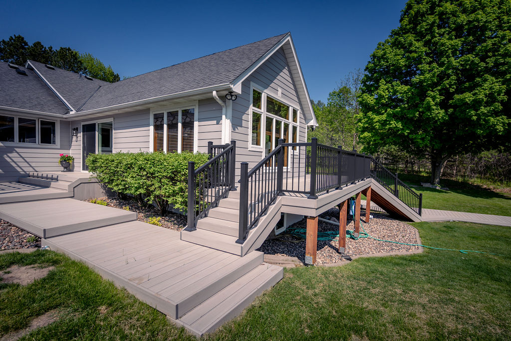 Multi-level deck wrapping around a house with PVC decking and aluminum railing.