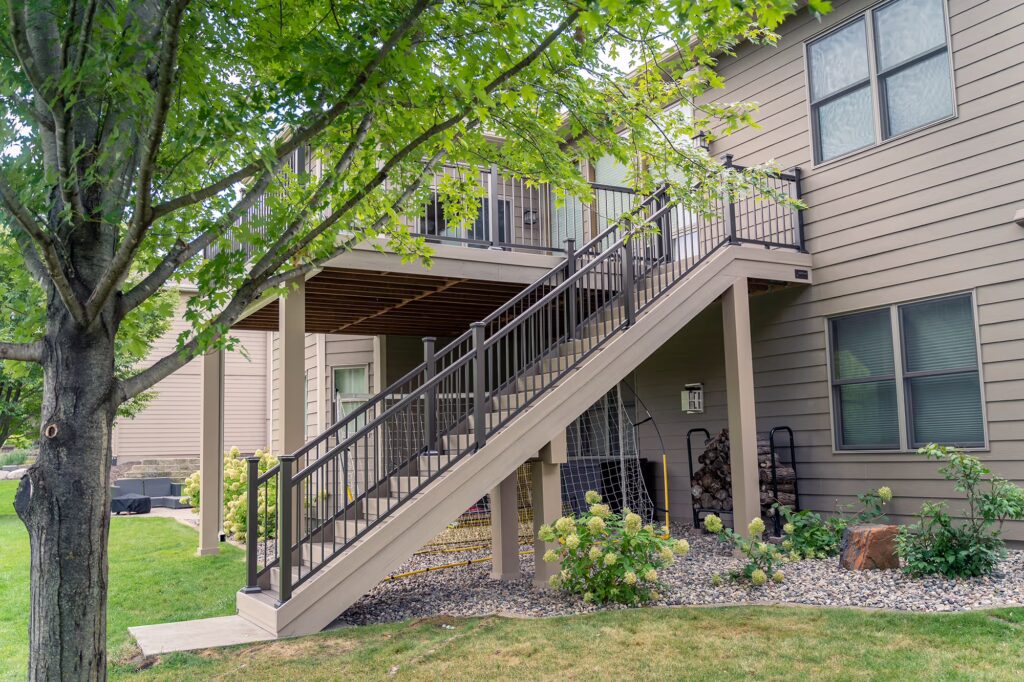 Side view of composite deck staircase with aluminum railing and a small cement slab landing. 