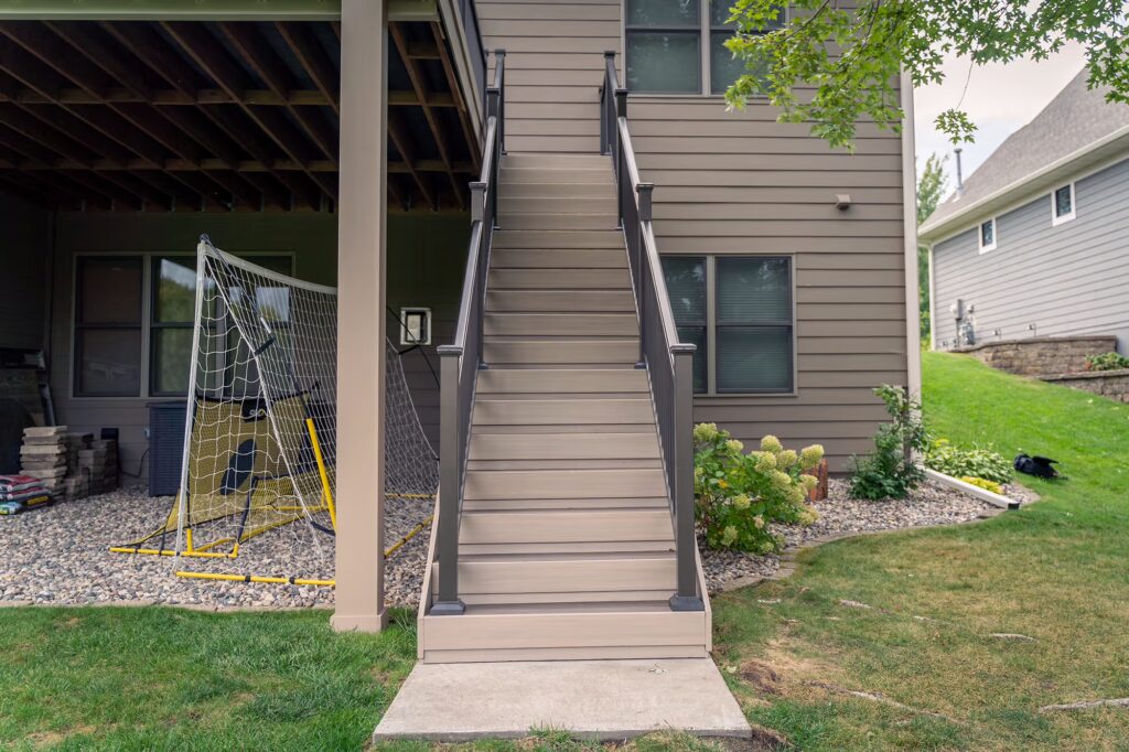 Front view of duo-tone composite deck stairs using TimberTech Advanced PVC with a cement pad landing. 