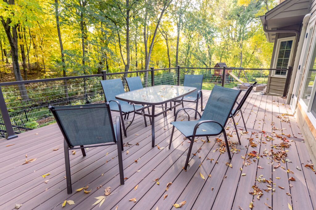 TimberTech Advanced PVC deck with dining furniture surrounded by fall foliage. 