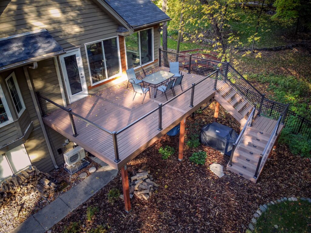 Low-maintenance deck with aluminum cable railing and an L-shaped staircase with integrated riser lights. 