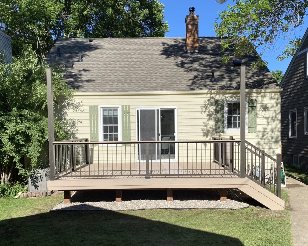 Back view of a home with a low deck and tall posts for bistro lights.
