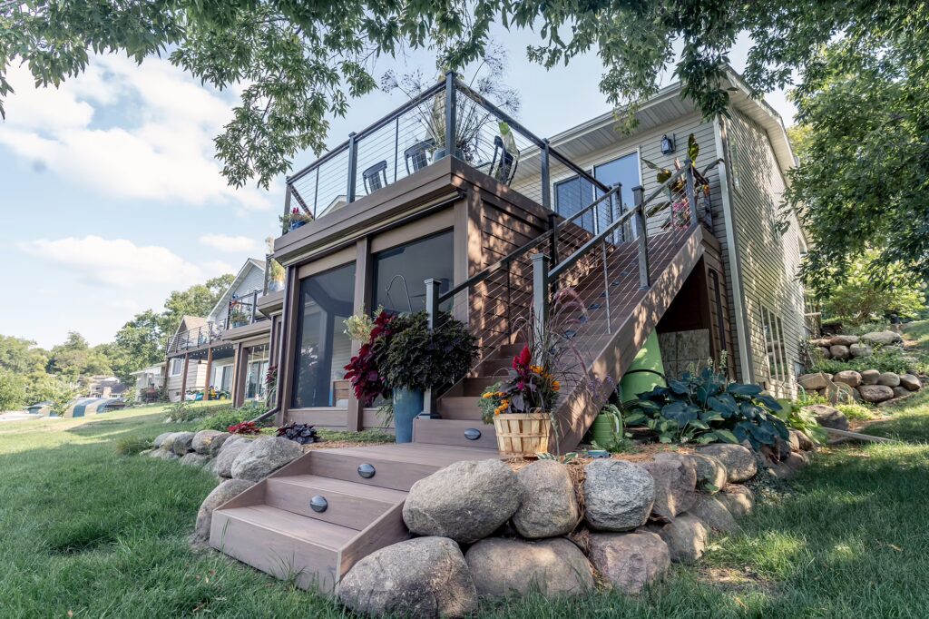Bottom of composite deck staircase with large rock landscaping. 