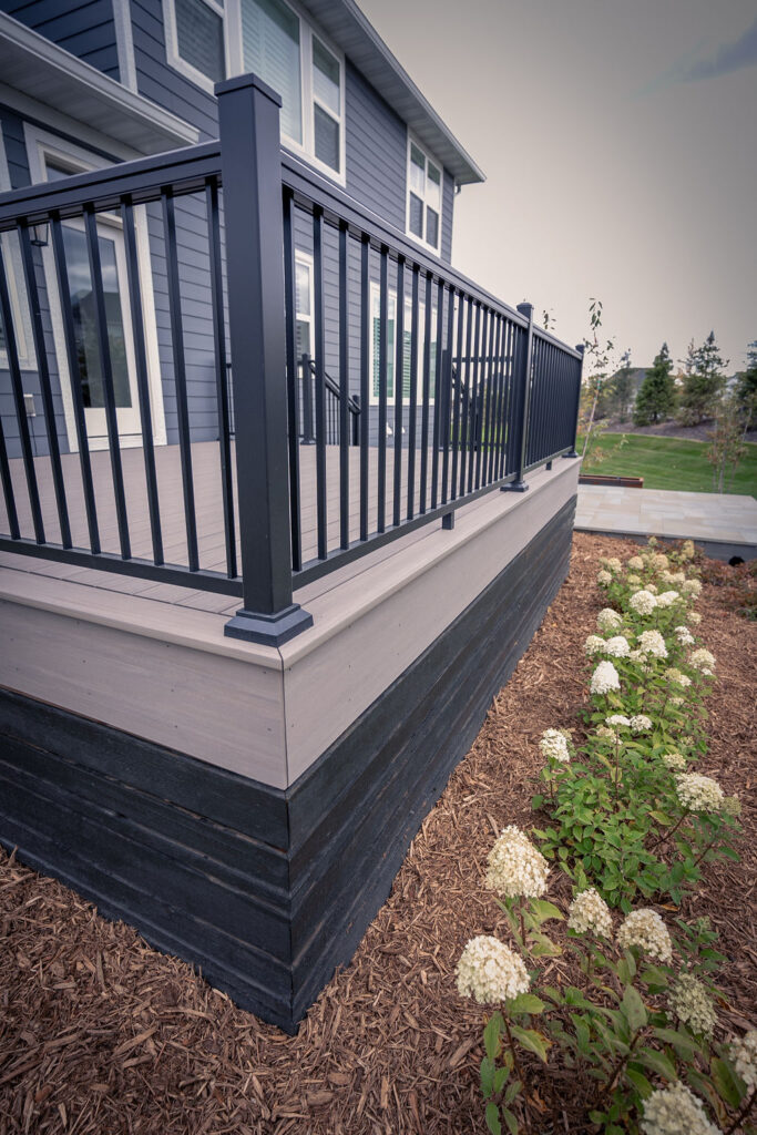 Front of low TimberTech Composite deck with freshly planted hydrangea bushes and mulch. 