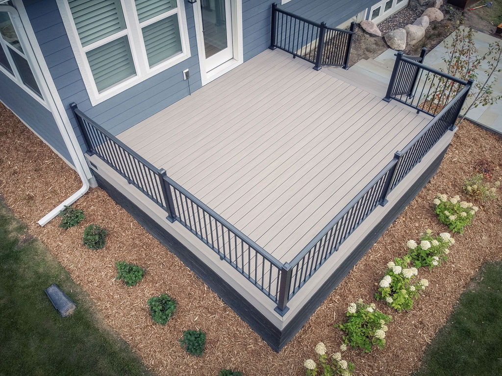 Aerial view of a low square composite deck with aluminum railing and surrounded by fresh landscaping.