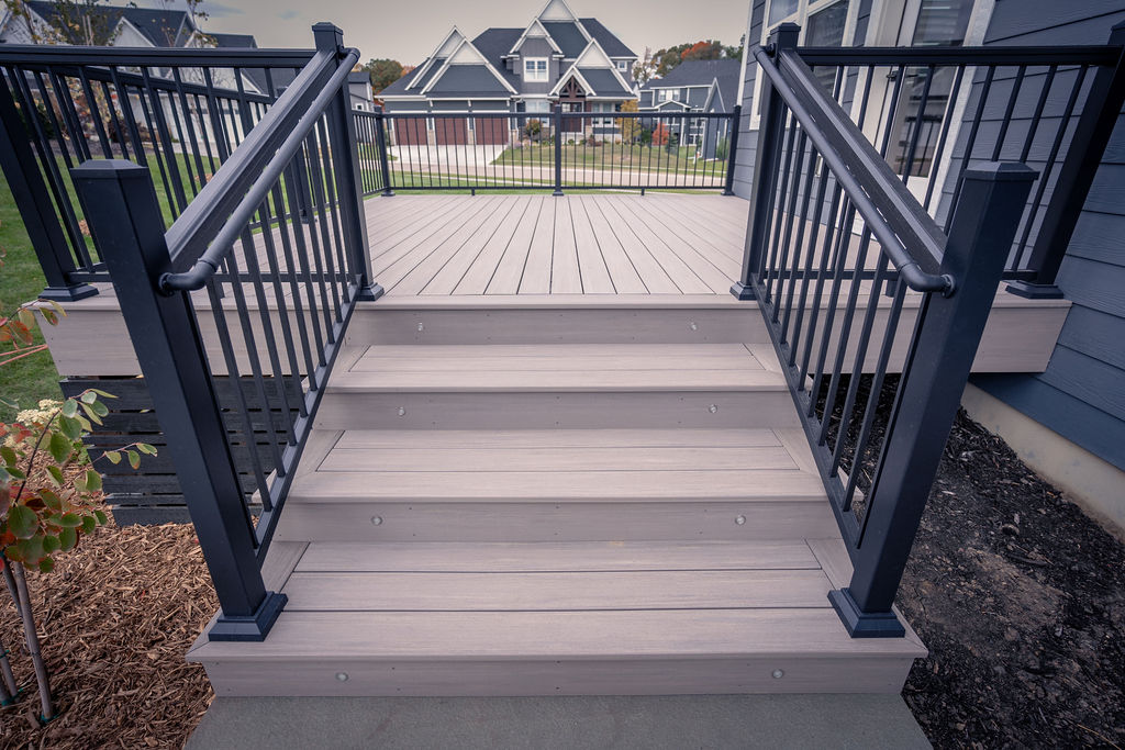 Front view of staircase on a low composite deck with aluminum picket railing and integrated riser lights. 