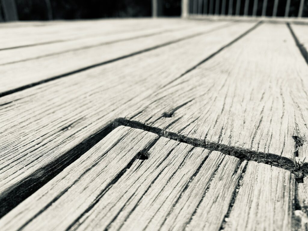 Cracked and faded wood deck highlighting the hidden costs of cheap deck materials.